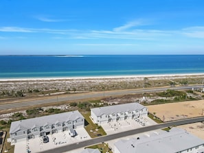 A coastal residential area with houses, a beach, and a road.