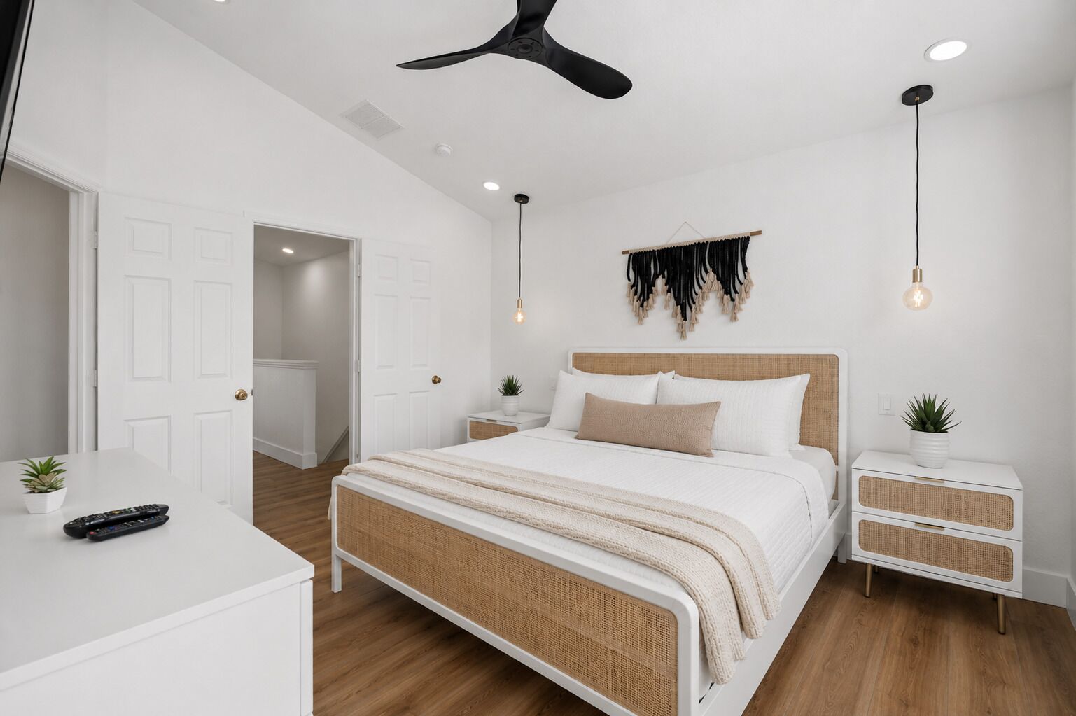 Un dormitorio moderno con cama, mesitas de noche, ventilador de techo e iluminación montada en la pared.