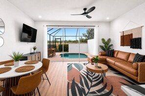 Ein modernes Wohnzimmer mit Pool, Ledersofa, Essbereich und Fernseher.