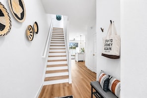 A staircase leading to a kitchen area with a white wall and a hanging sign. - Windsor Hills Townhome - Theme Bedroom - Private Heated Pool - 2 Miles to Disney (Kissimmee)