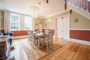 A dining area with a wooden table and chairs, a chandelier, and a staircase. - The Old School House, Friston (Friston)
