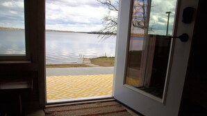Blick durch eine Tür auf einen See, ein gemustertes Teppich im Boden und eine Tür mit Griff.