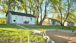 A house with a front porch, a yard with a stone wall, and a small pool.