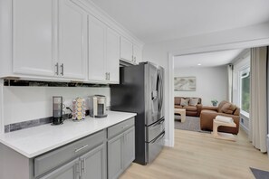 Una cocina moderna con armarios grises, un refrigerador de acero inoxidable y una cafetera.