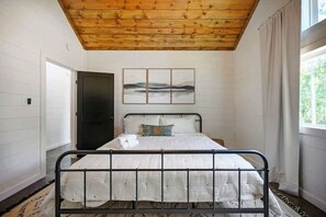 Ein Schlafzimmer mit einem Bett, Holzboden, einer Tür, einem Fenster und einem Wandbild.