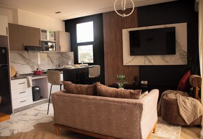 Una cocina moderna con comedor, un sofá y un televisor montado en la pared.