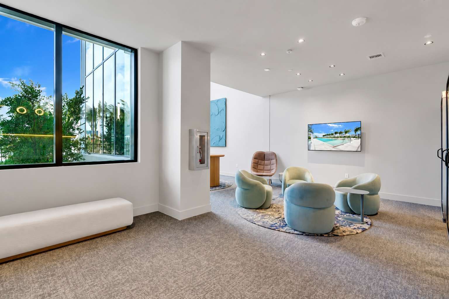 Un interior moderno con un ventanal grande, una zona de estar y un televisor.