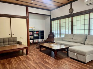 A living room with a sofa, a coffee table, a bookshelf, and a guitar. - Goodies Ella (Shimonoseki)