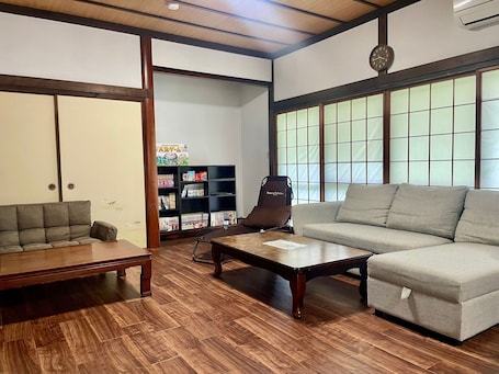 A living room with a sofa, a coffee table, a bookshelf, and a guitar.