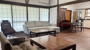 Una sala de estar con sofá, sillón, mesa de centro y un comedor con sillas y una mesa.