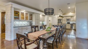 A spacious kitchen with a central island, white cabinetry, and modern appliances. - Spacious retreat, pool and hot tub within walking distance of Lake Travis. (Spicewood)