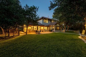 Ein Haus mit Terrasse, überdachter Sitzgelegenheit und gepflegtem Rasen.