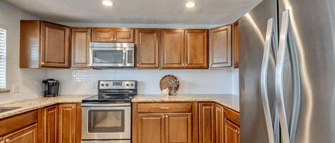 A kitchen with wooden cabinets, stainless steel appliances, and a tiled floor.