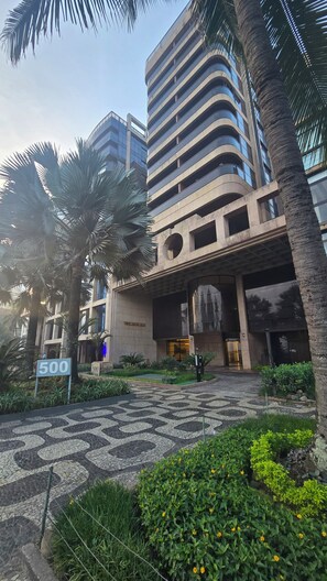 A modern building with a large entrance, palm trees, and a mosaic-patterned pavement. - Vieira Souto 500: Luxury Oceanfront Sanctuary with Panoramic Views in Ipanema (Rio de Janeiro)