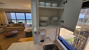 Eine moderne Küche mit integriertem Geschirrspüler, ein Essbereich mit Meerblick und ein Wohnzimmer mit Sofa und Couchtisch.