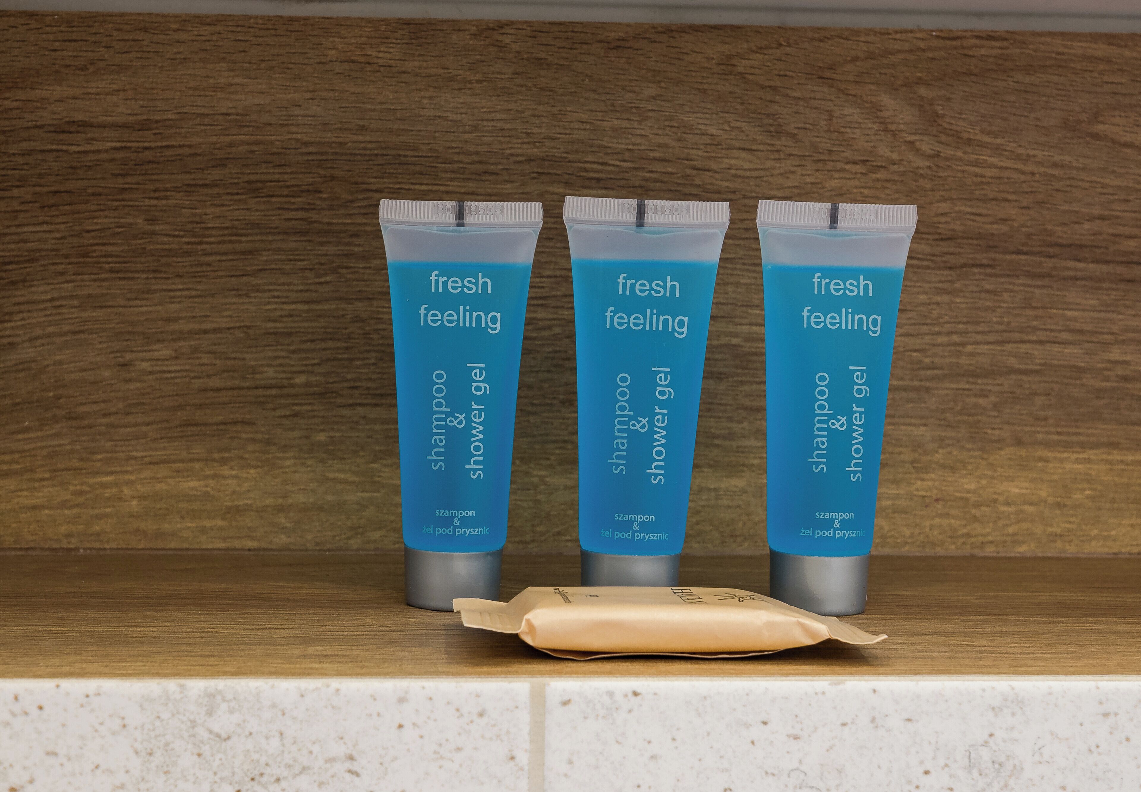 Drei Flaschen Shampoo und Duschgel auf einem Regal.
