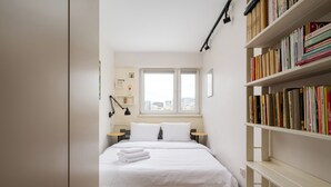Ein Schlafzimmer mit einem Bett, Nachttischen, einem Bücherregal und einem Fenster.