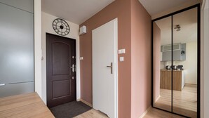 Ein modernes Interieur mit einer Holztür, einer Uhr und einer Schiebetür aus Glas, die in einen Küchenbereich führt.