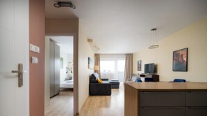 Ein modernes Hotelzimmer mit Holzboden, einer Couch, einem Fernseher und einem Schreibtisch.