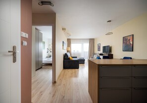 A modern hotel room with a wooden floor, a sofa, a TV, and a desk. - Mokotów Cozy Living Apartment (Warszawa)