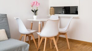 A modern room with a grey sofa, white chairs, a small table with a potted plant, and a window with a view. - Rondo ONZ Urban Core Apartment (Warszawa)
