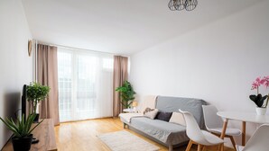 A modern living room with a sofa, chairs, a small table, and potted plants. - Rondo ONZ Urban Core Apartment (Warszawa)