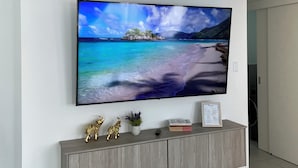 A flat-screen TV mounted on a white wall above a grey console with decorative items. - Delightful 3-bedroom apartment in Tumbaco, Quito (Quito)