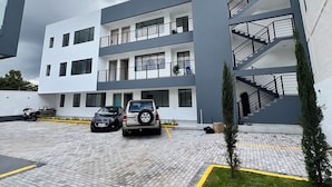 A modern building with a parking area, a staircase, and a small lawn. - Delightful 3-bedroom apartment in Tumbaco, Quito (Quito)