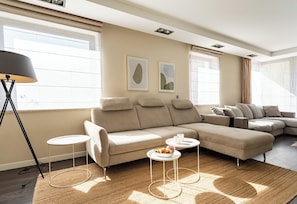 Un salon moderne avec un canapé d’angle, une table basse ronde et un lampadaire.