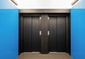 Ein Aufzug mit zwei Türen, blauen Wänden und einem gefliesten Boden.