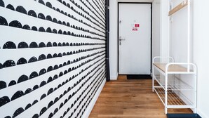 A hallway with a patterned wall, a door with a sign, and a white metal bench.