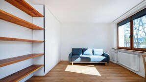 A room with a wooden floor, a sofa, and built-in shelves.
