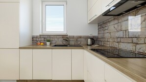 A kitchen with a window, stone backsplash, and modern appliances. - Raginisa Superior Apartment (Szczecin)