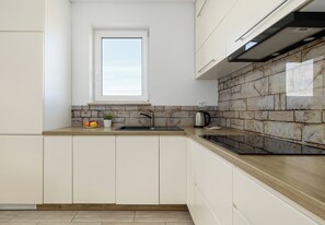 Eine Küche mit Fenster, Steinrückwand und modernen Geräten.