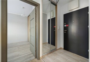 Ein Zimmer mit einer Schiebetür aus Glas, einer dunklen Tür und einem hellen Holzboden.