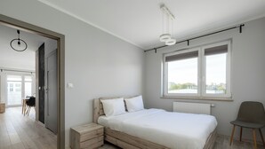 A modern bedroom with a wooden bed, a window with a view, a chair, and a desk. - Raginisa Superior Apartment (Szczecin)