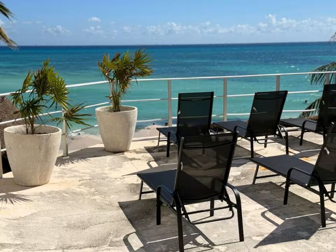 En terrasse med stole og plantekasser med udsigt over stranden.