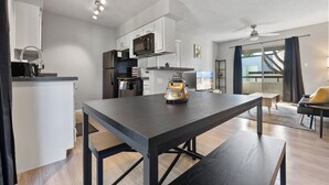 Une cuisine moderne avec des meubles blancs, un four à micro-ondes et un coin repas comprenant une table et un banc.