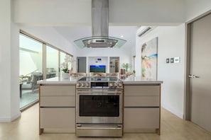 A modern kitchen with a built-in oven, a glass cooktop, and a stainless steel range hood.