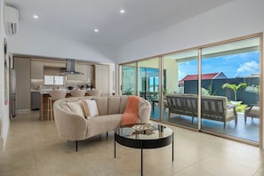 A modern living room with a sofa, a coffee table, and a sliding glass door leading to an outdoor patio.