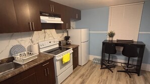A kitchen with dark wooden cabinets, a white stove, a refrigerator, and a small table with chairs.