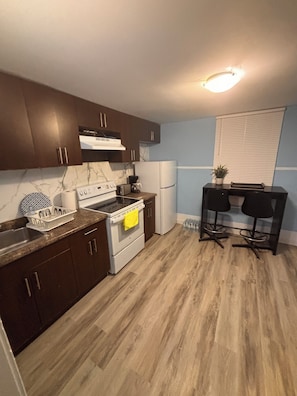 A kitchen with dark wooden cabinets, a white stove, a refrigerator, and a small table with chairs. - Two story House: 3 Bed room 1/5 Bathroom (Winnipeg)