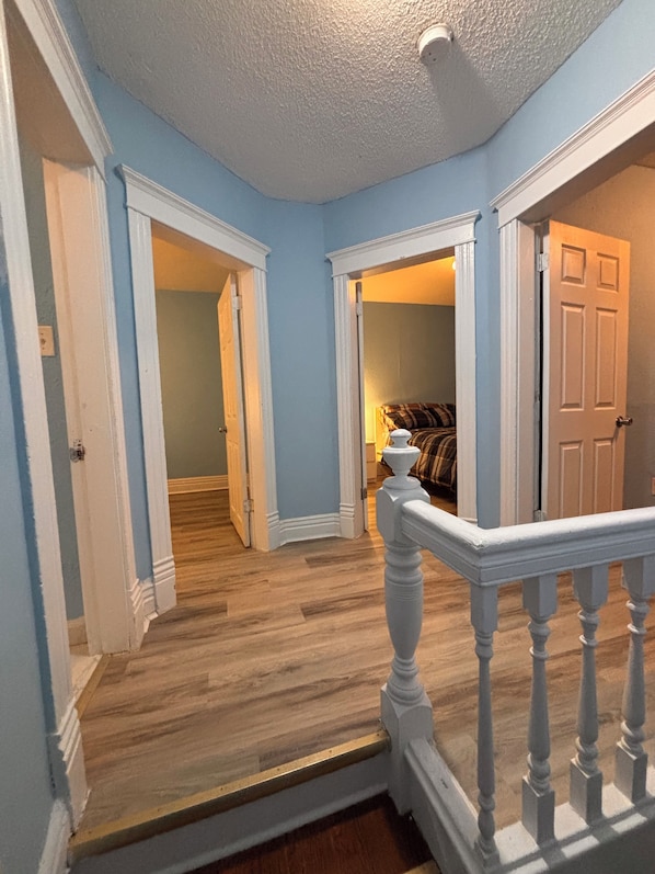A hallway with wooden flooring, white walls, and a white railing. - Two story House: 3 Bed room 1/5 Bathroom (Winnipeg)