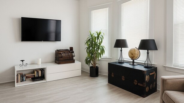 A modern living room with a flat-screen TV, a vintage typewriter, a potted plant, two lamps, and a globe on a wooden chest. - Detroit 4BR Home | Bathtub and Pet Friendly Stay (Detroit)