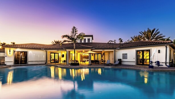 A resort with a swimming pool, outdoor seating, and a well-lit building.