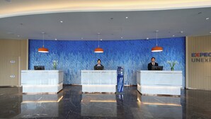 A reception area with three reception desks, blue mosaic walls, and overhead lighting.