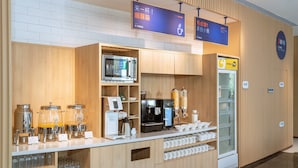 A modern kitchenette with a microwave, coffee machine, and a beverage dispenser.