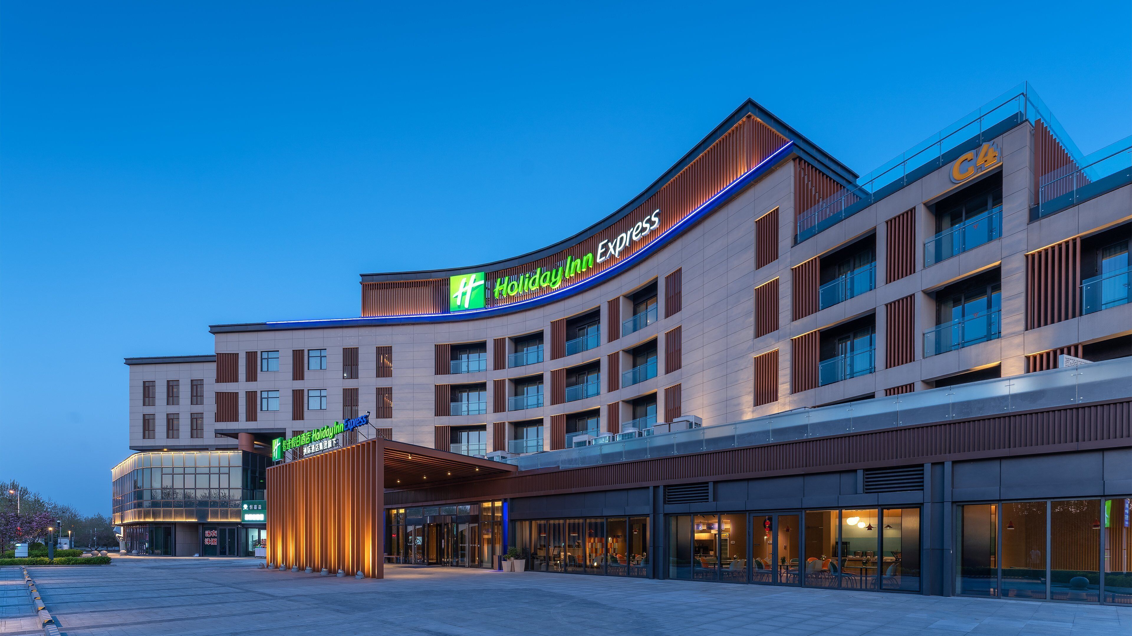 Un hôtel Holiday Inn Express au design moderne, caractérisé par une façade incurvée imposante, de grandes fenêtres et un hall d’entrée spacieux.