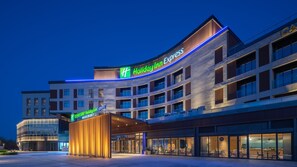 Un hotel Holiday Inn Express de diseño moderno, con una señalización destacada, una entrada cubierta y una fachada bien iluminada.