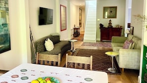 Ein Wohnzimmer mit Bett, Fernseher, Treppe und Essbereich.